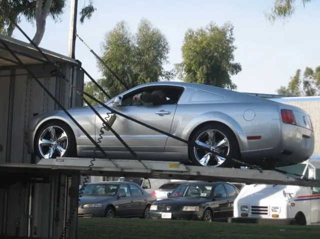 A silver Ford Mustang loaded onto a car carrier for shipment